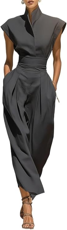 A woman dressed in a stylish, dark gray jumpsuit with a high collar and wide, cropped sleeves, paired with strappy high heels.