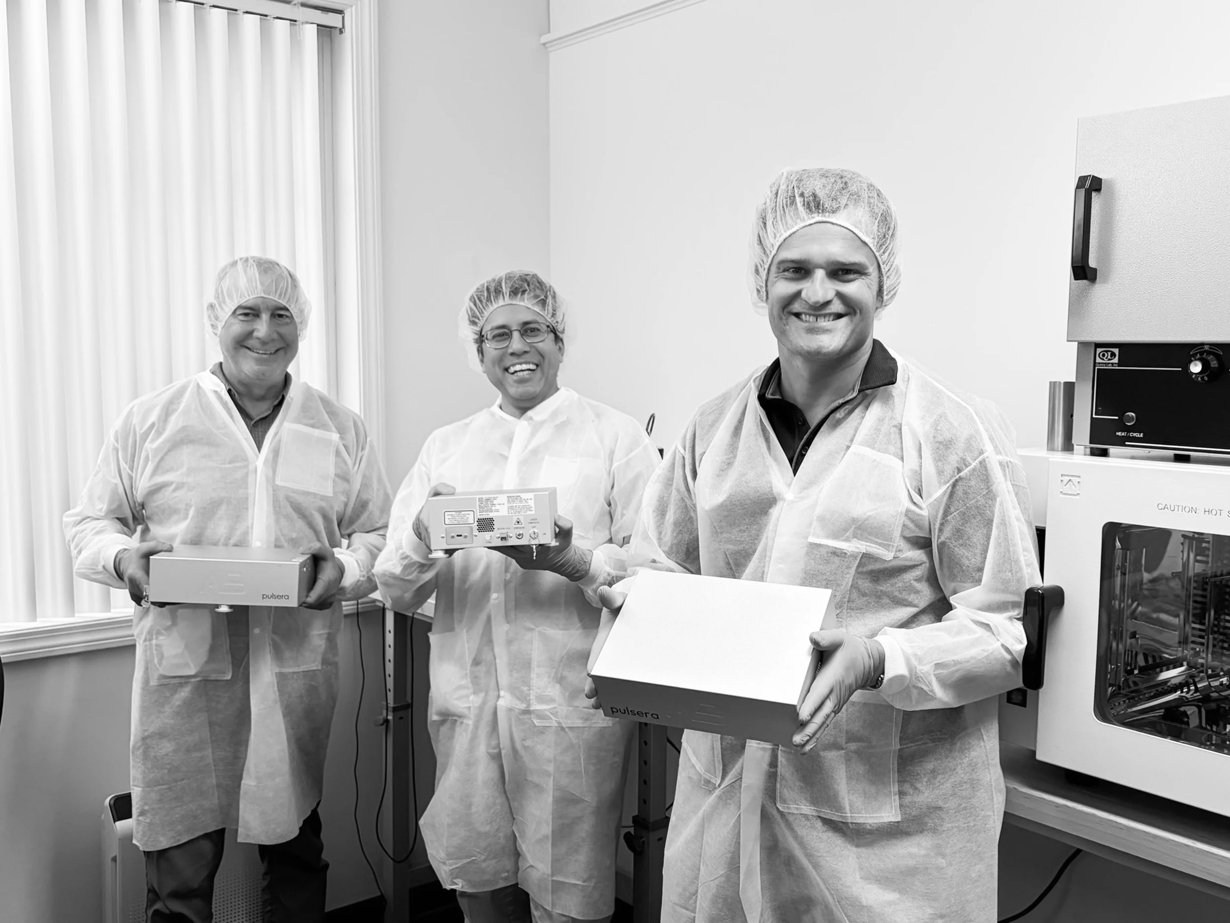 AB Photonics team members holding Pulsera laser systems in their laboratory.