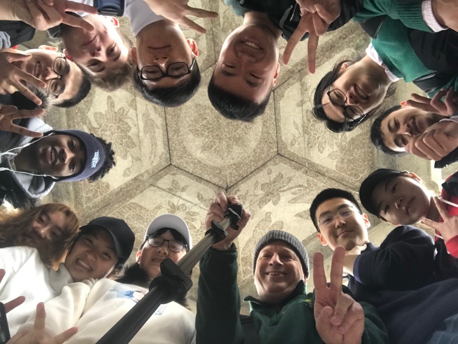 Photo of Joe with a group of a dozen students forming a circle and taken during a hike with Chinese undergraduates and students visiting from America
