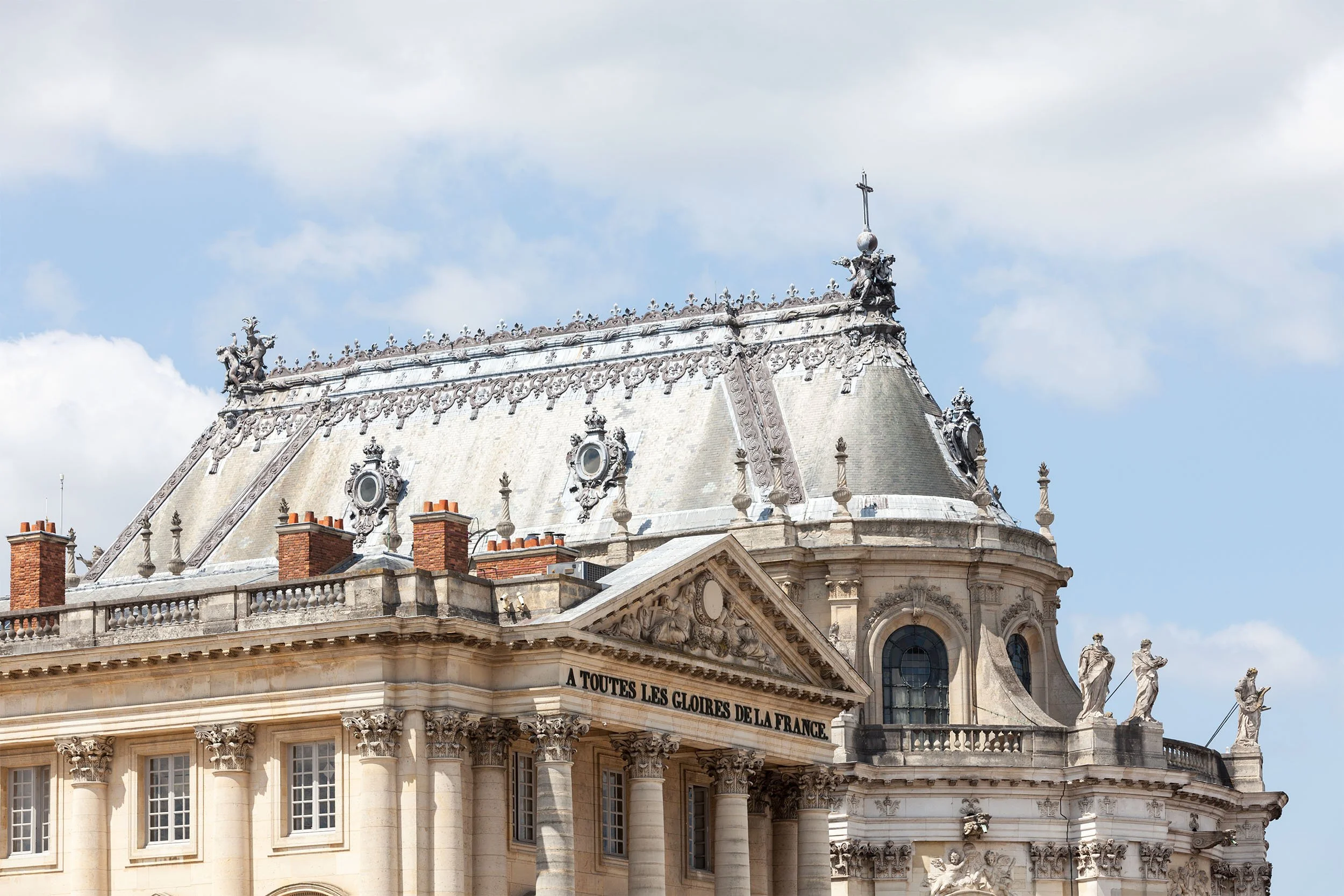 Ornate classical stone building at the Palace of Versailles, France, under a blue sky — the source photograph for a Photo-Anagram created with the BeMuze app.