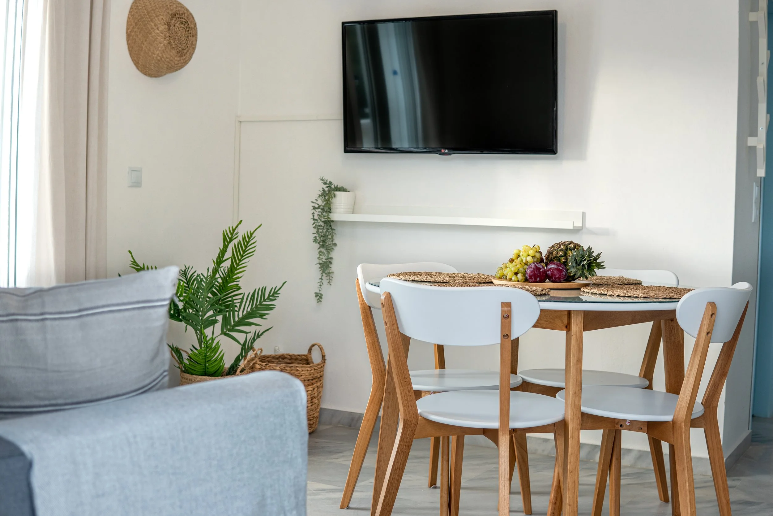 Living room with a dining table, fruit centerpiece, and wall-mounted television.