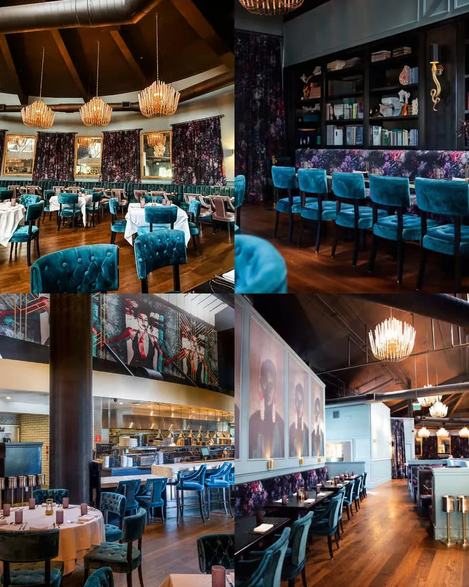 Interior of a stylish restaurant with blue velvet chairs, dark wood floors, decorative curtains, and modern art and lighting fixtures.