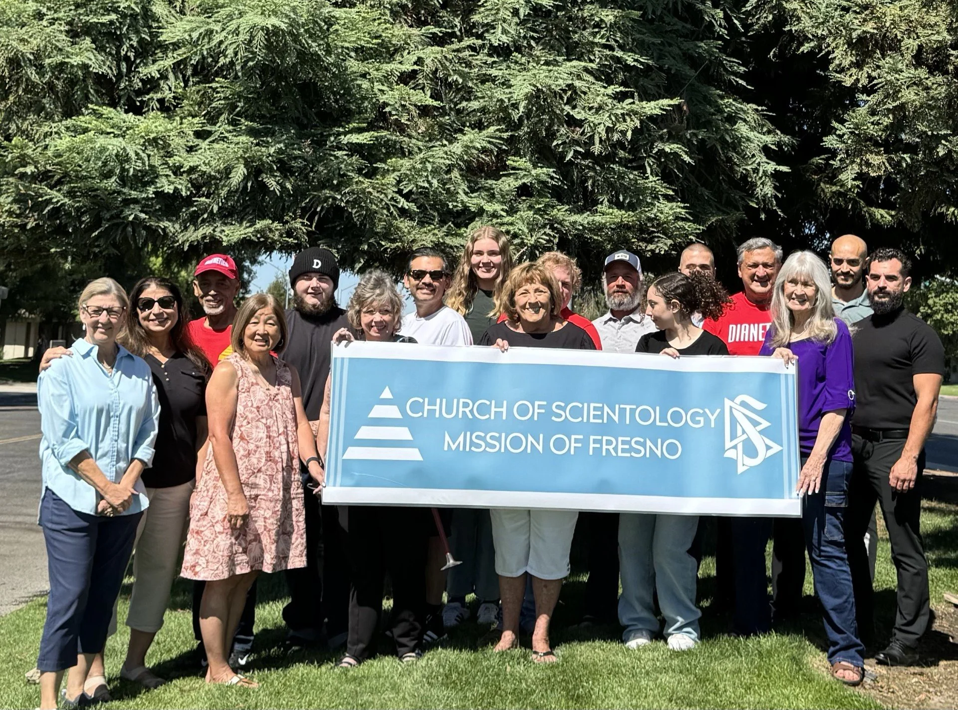 Fresno MIssion STaff, Volunteers and Parishioners hold up the Mission's banner for a group photo.