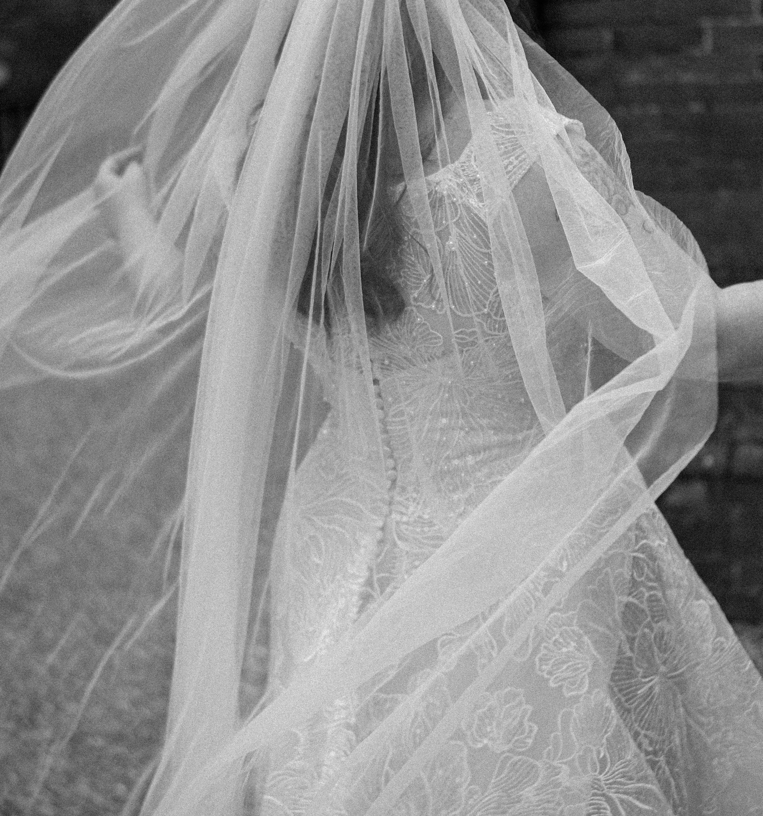 Close-up of a delicate, layered, white fabric with intricate floral embroidery and sheer, flowing material.