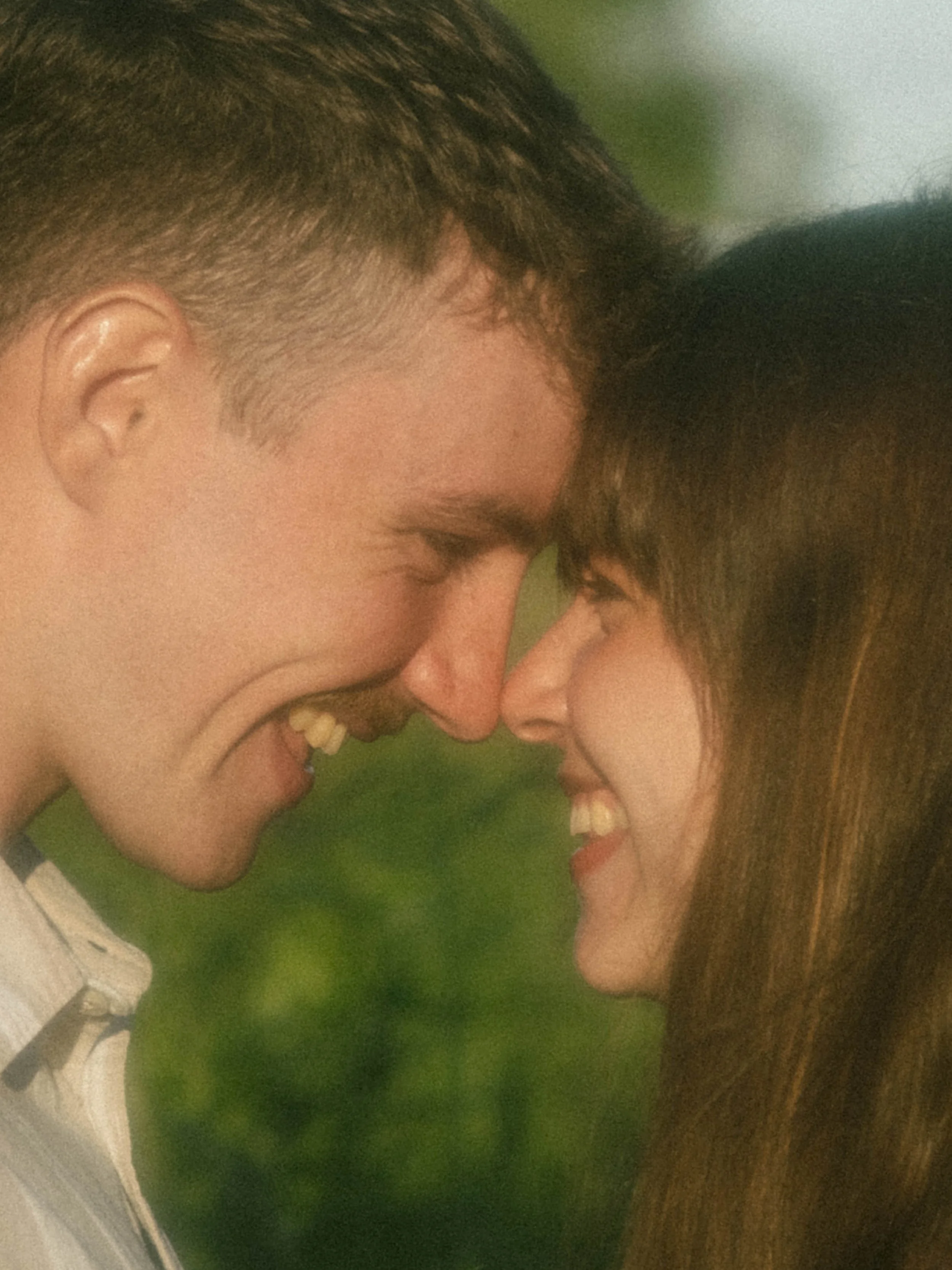 A close-up of a couple touching foreheads, smiling and sharing a joyful moment.