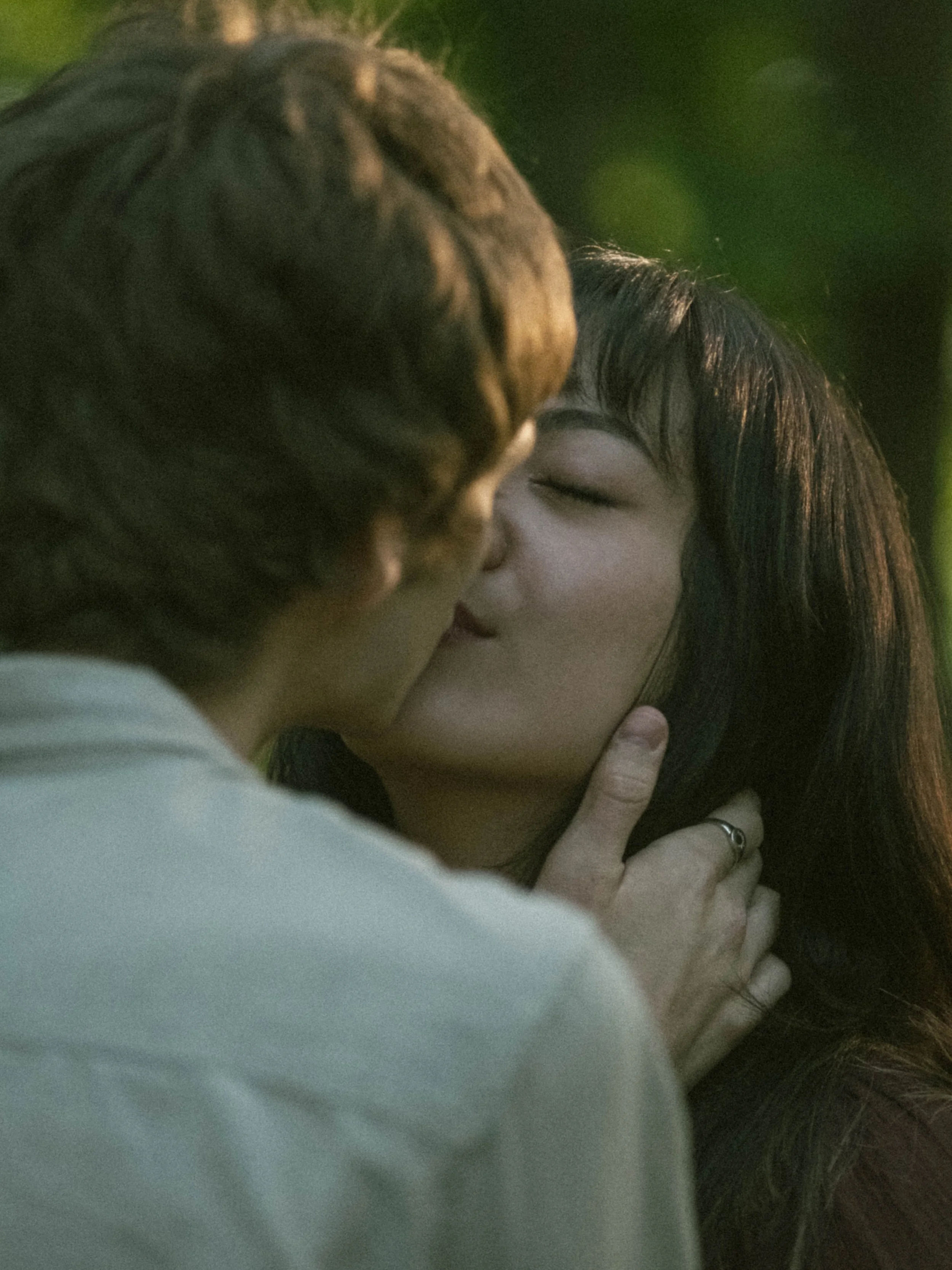 A close-up photo of a couple kissing, with the woman's face visible and her eyes closed, and a man's arm wrapped around her.