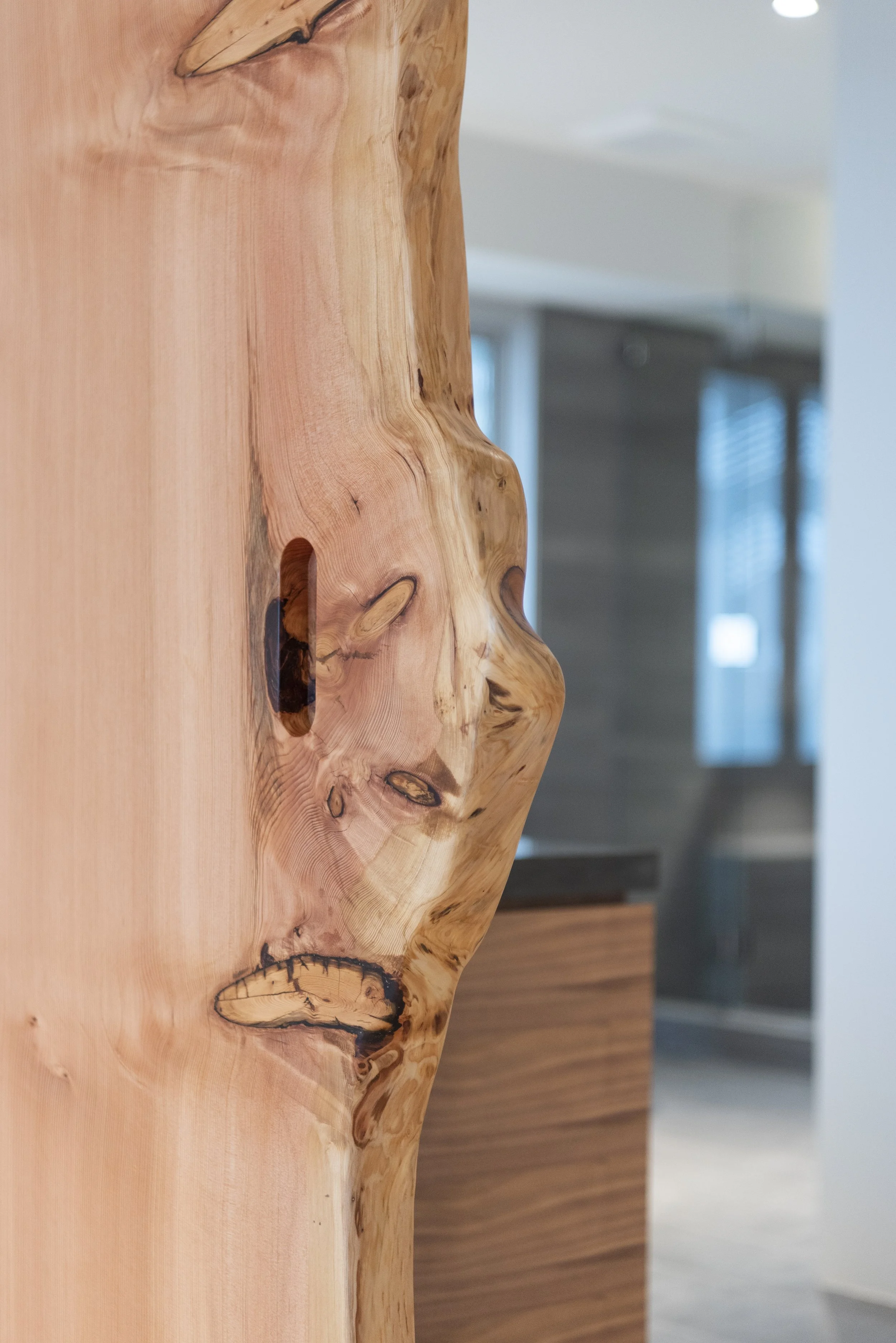 Close-up of a wooden table with natural grain and knots, with a blurred background of an interior room.