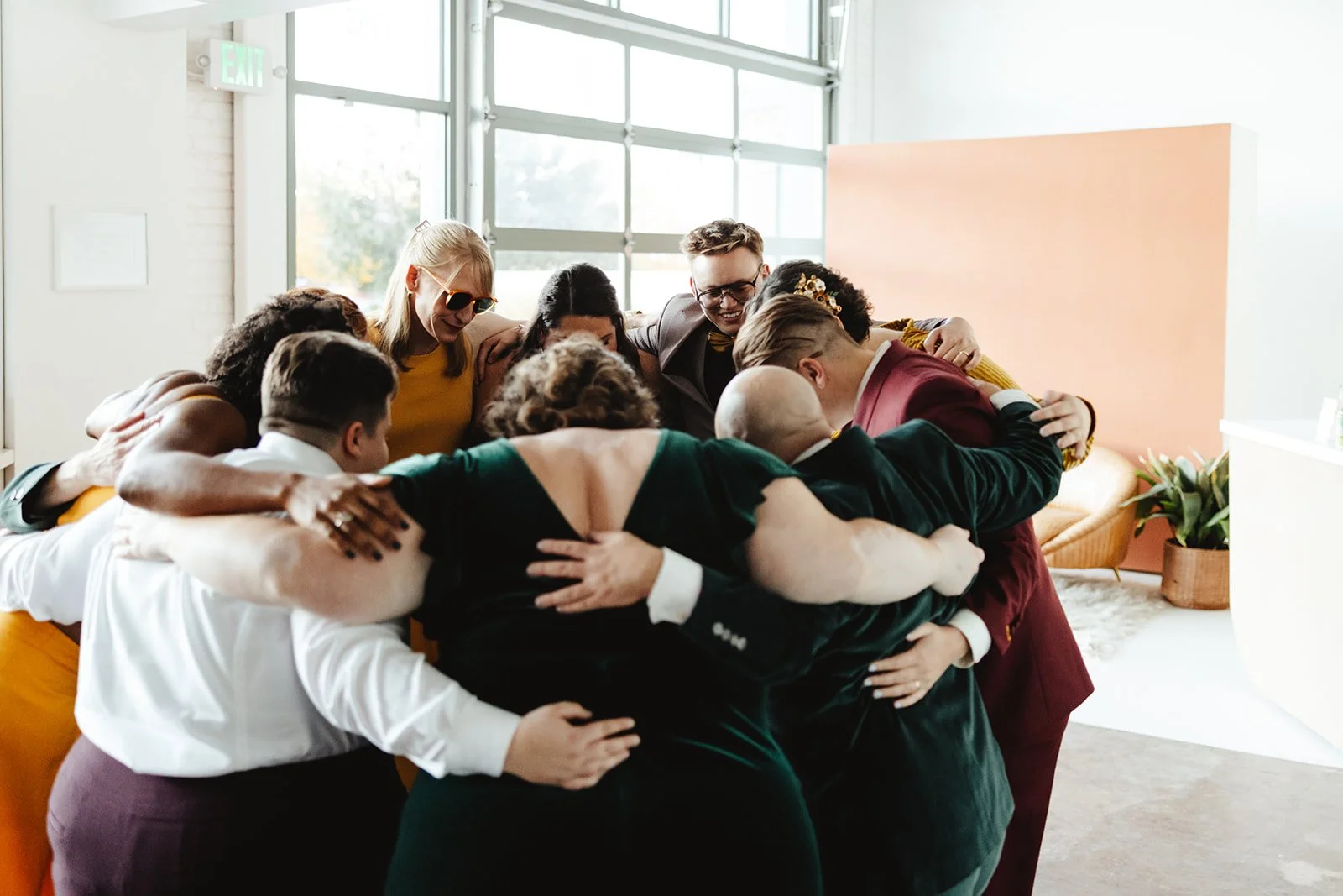 A group comes together in a hug centering around a just married queer couple