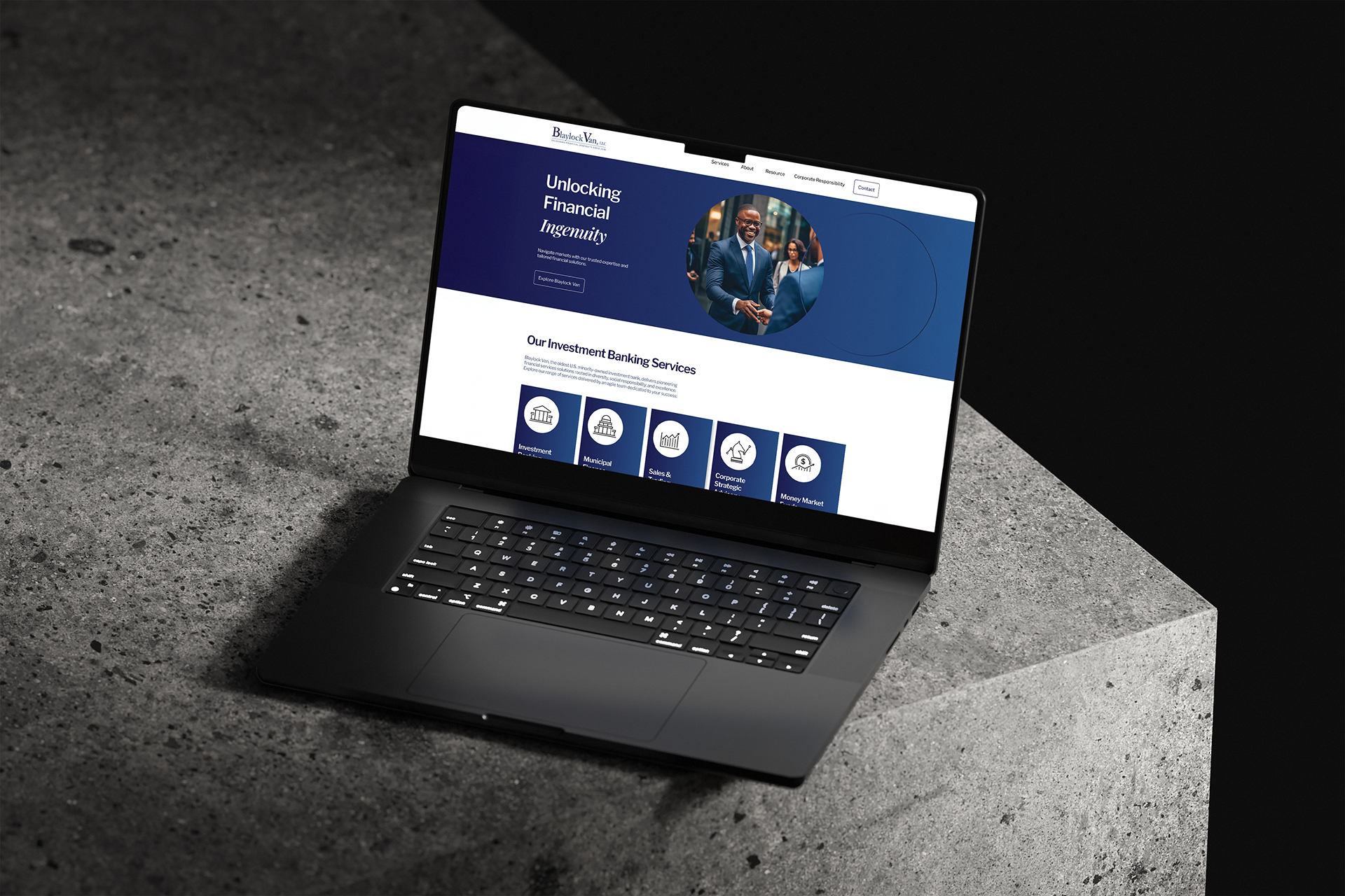 A laptop on a concrete surface displays a website for a financial services company with a blue and white color scheme, featuring a man in a suit in the header.