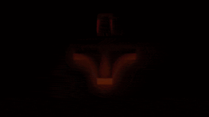 A dark scene with red light illuminating a face mask with glowing eyes, giving it a mysterious appearance.