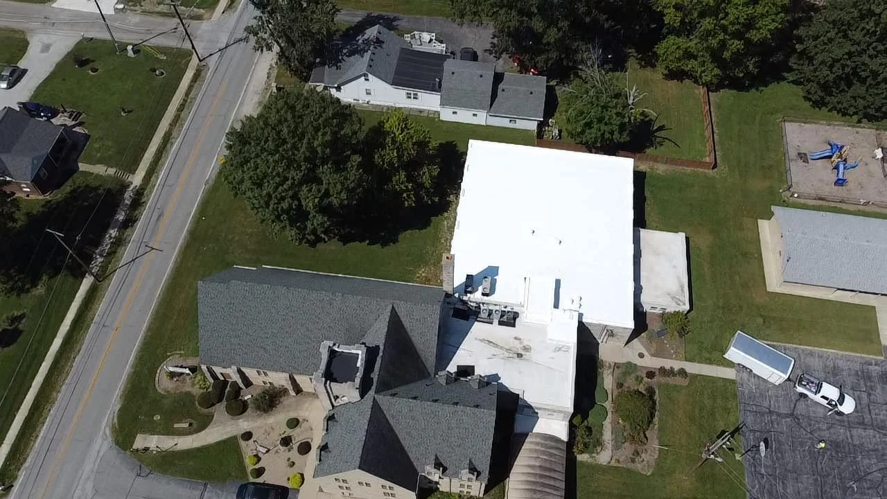 Aerial view of a neighborhood with several houses, trees, a playground, and a street with cars.