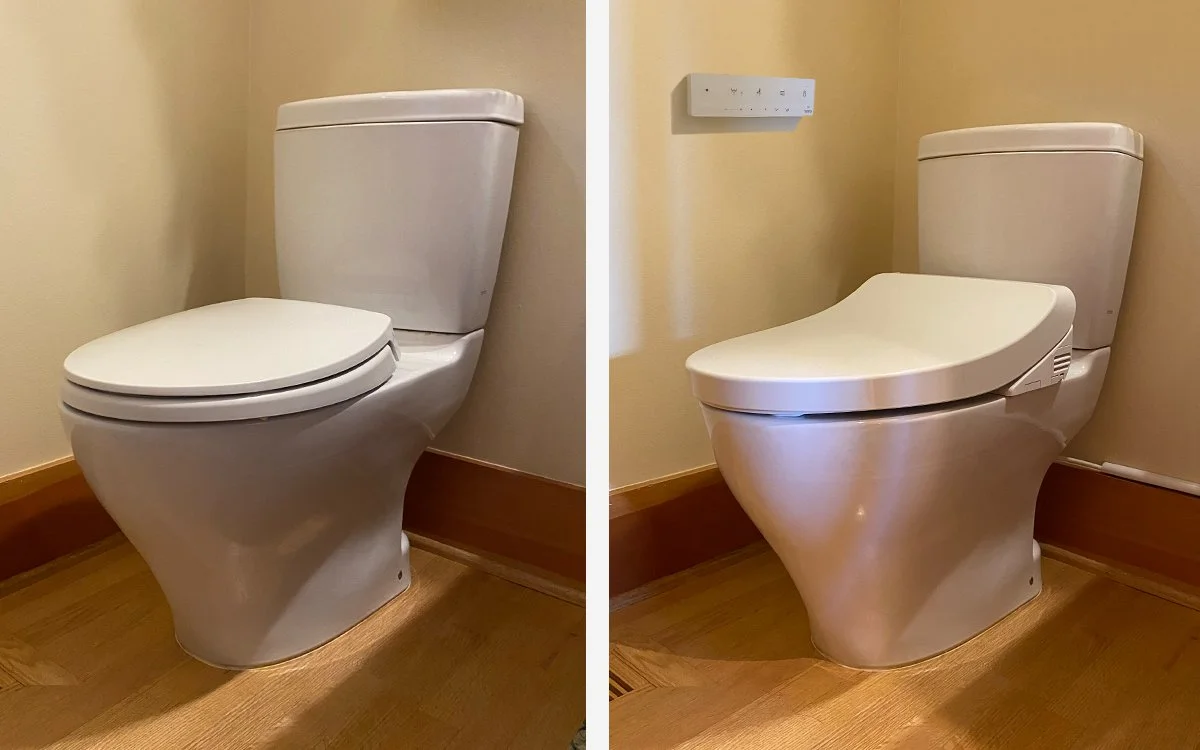 Comparison of a traditional toilet and a bidet toilet seat in a bathroom with hardwood flooring and beige walls.