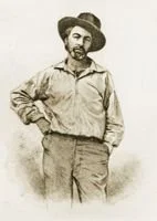 Historical black-and-white photograph of a man with a mustache, wearing a wide-brimmed hat, a long-sleeved shirt, and trousers, standing with one hand in his pocket.