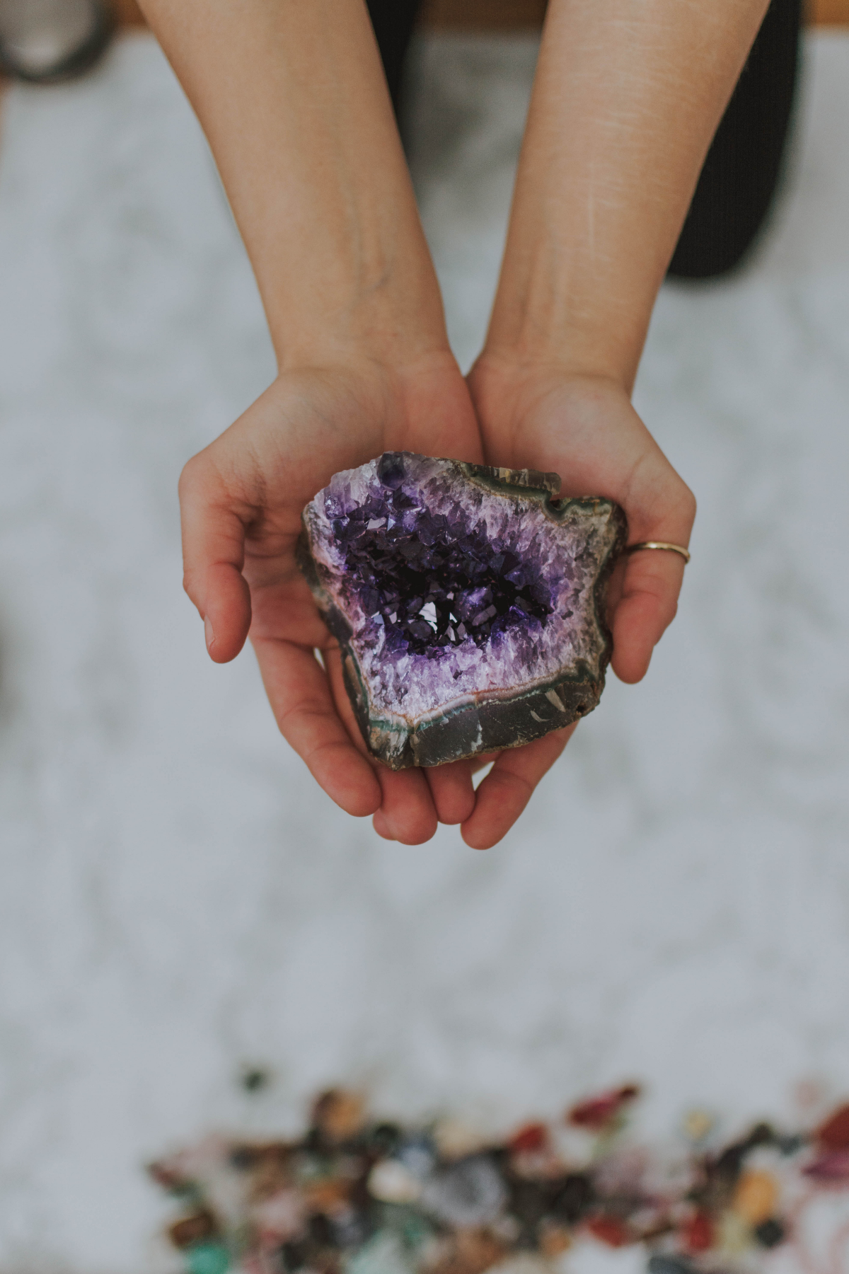 A person holding a large, purple and black geode with an intricate, crystalline interior.