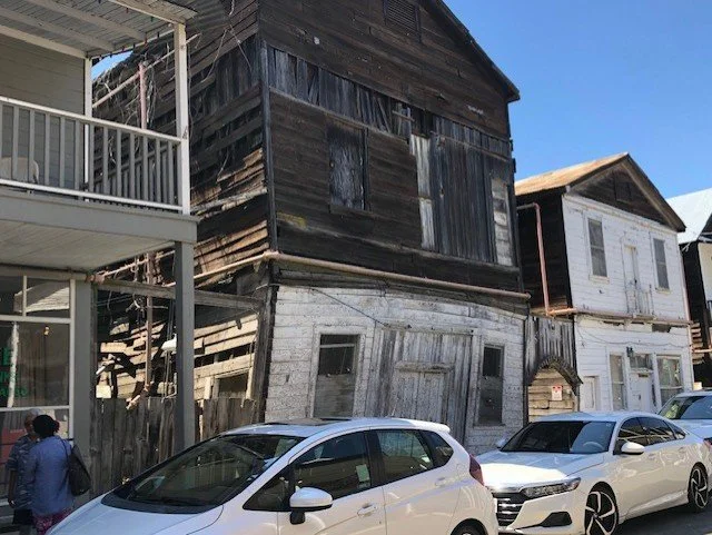 A row of cars parked in front of The Star Theater with peeling dark paint and boarded-up windows.