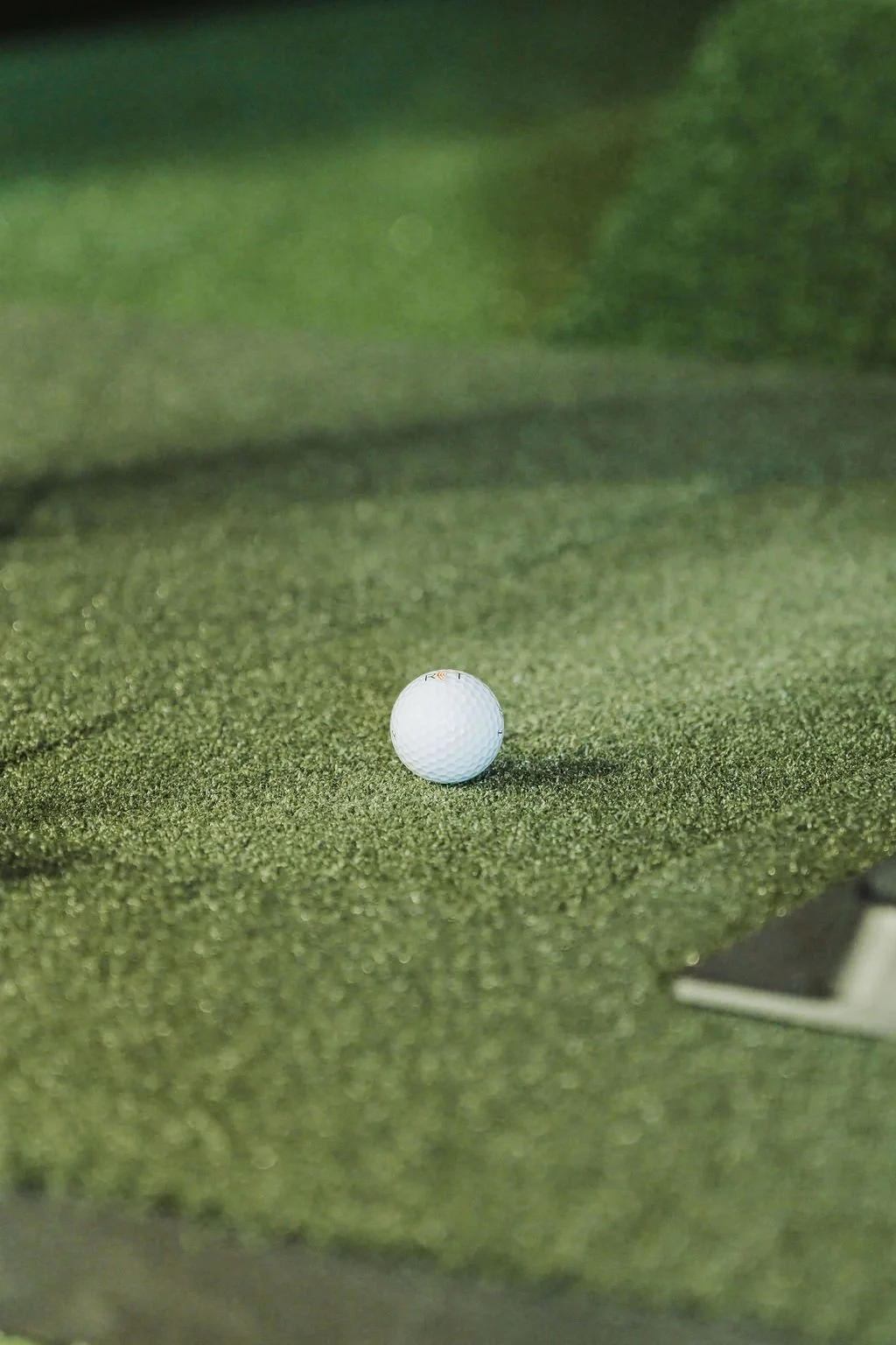 A white golf ball on a green putting surface.