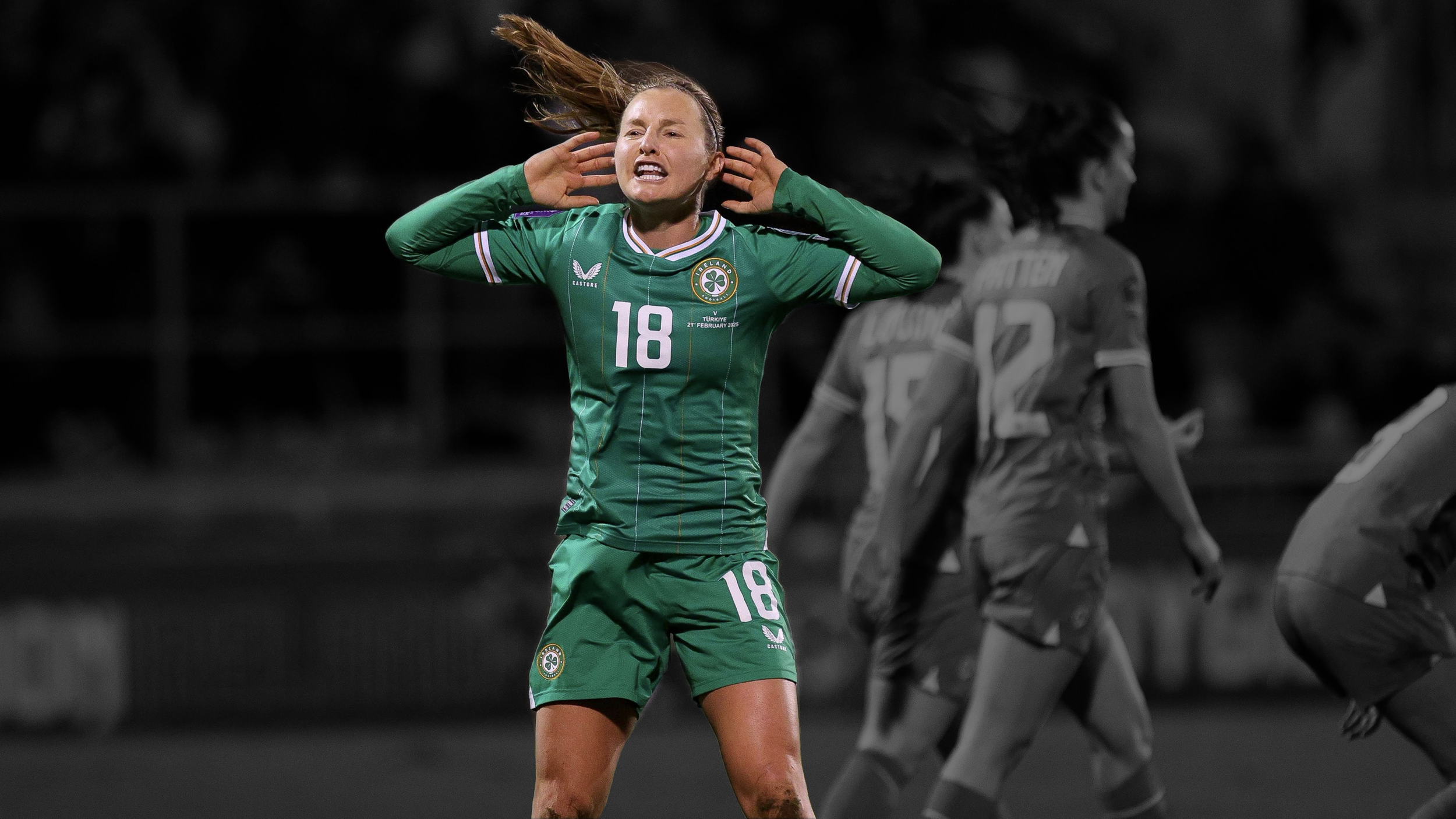 A female soccer player in a green jersey with the number 18, covering her ears with her hands during a night match.