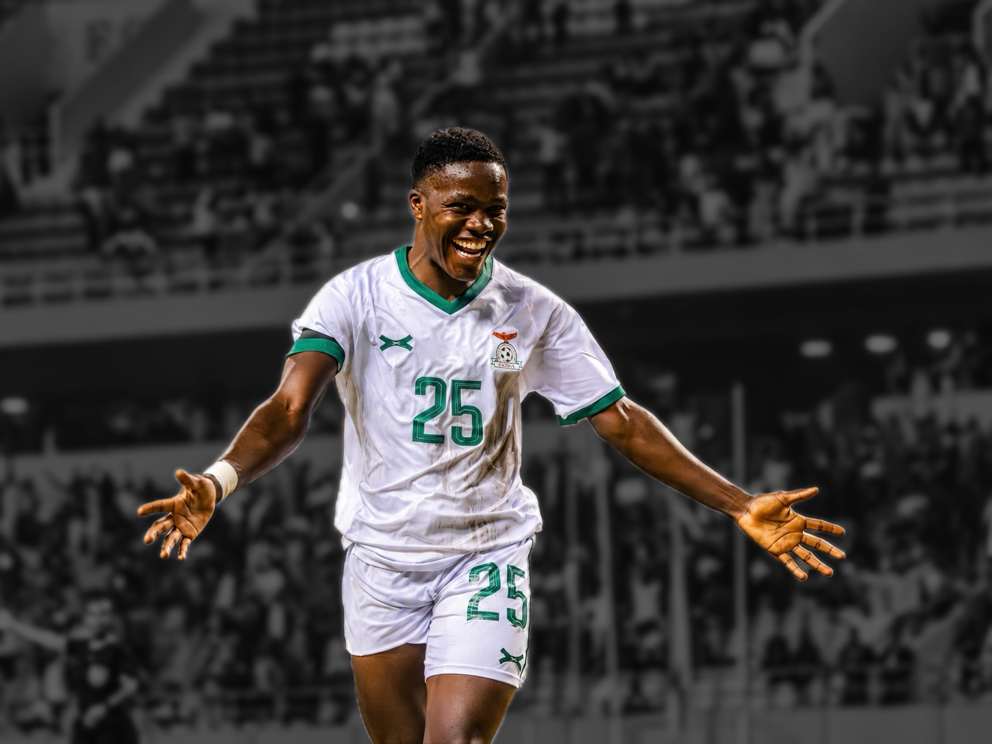 A smiling soccer player wearing a white jersey with the number 25 on it, on a soccer field with a crowd in the background.