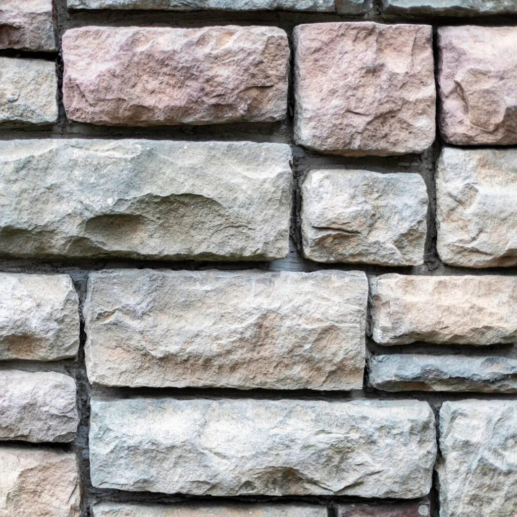 Close-up of a stone wall with rectangular bricks in shades of beige, light pink, and gray.