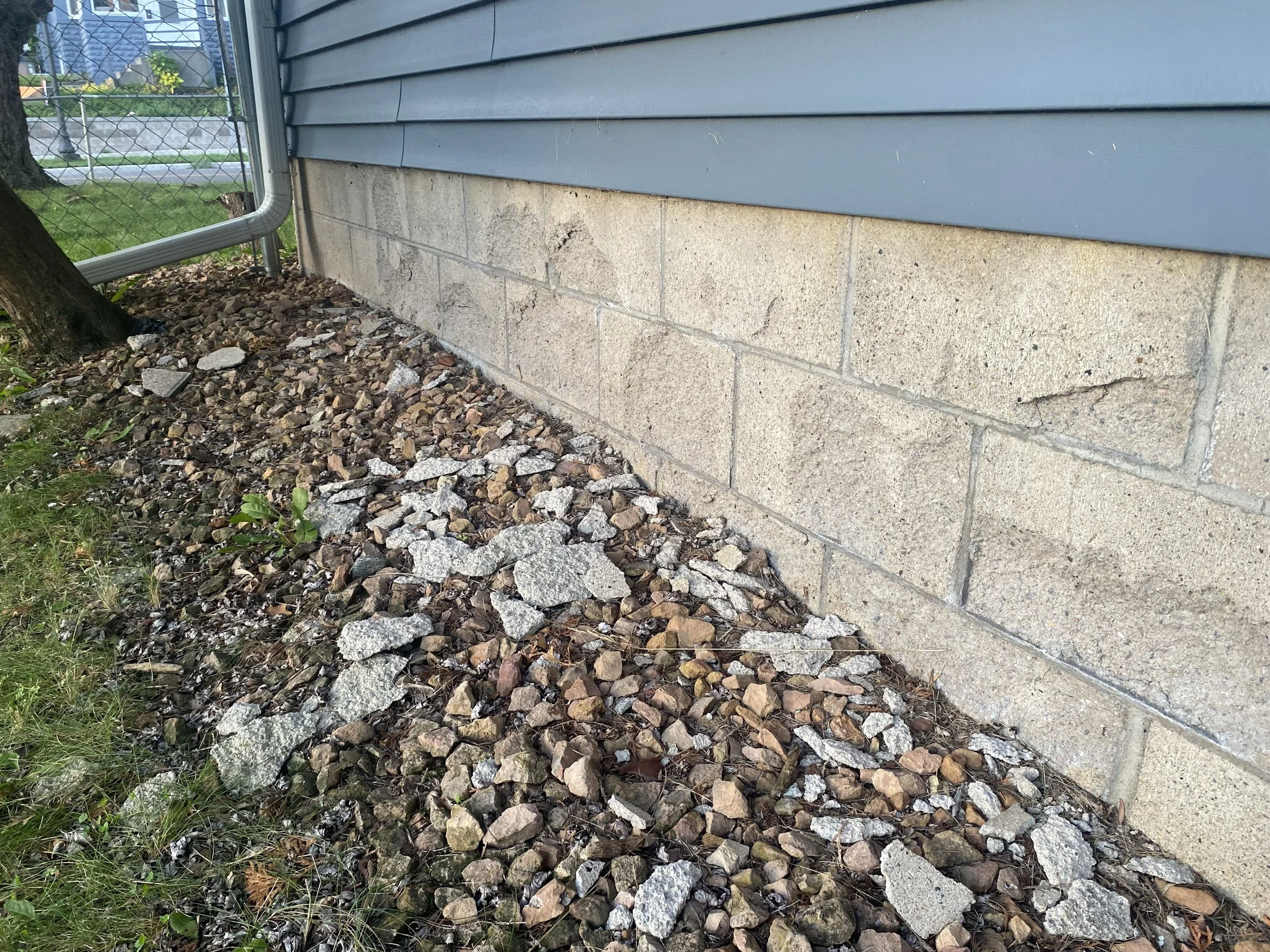 Foundation of a house with horizontal siding, concrete blocks, a gutter, and a yard in Apple Valley MN.