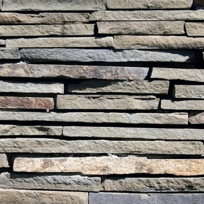 Close-up of a stacked stone wall with horizontal layers of gray and tan stones.