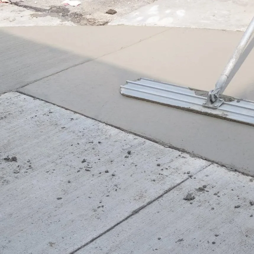 Close-up of concrete sidewalk with a patch of new concrete being poured, supported by a metal form and pole.