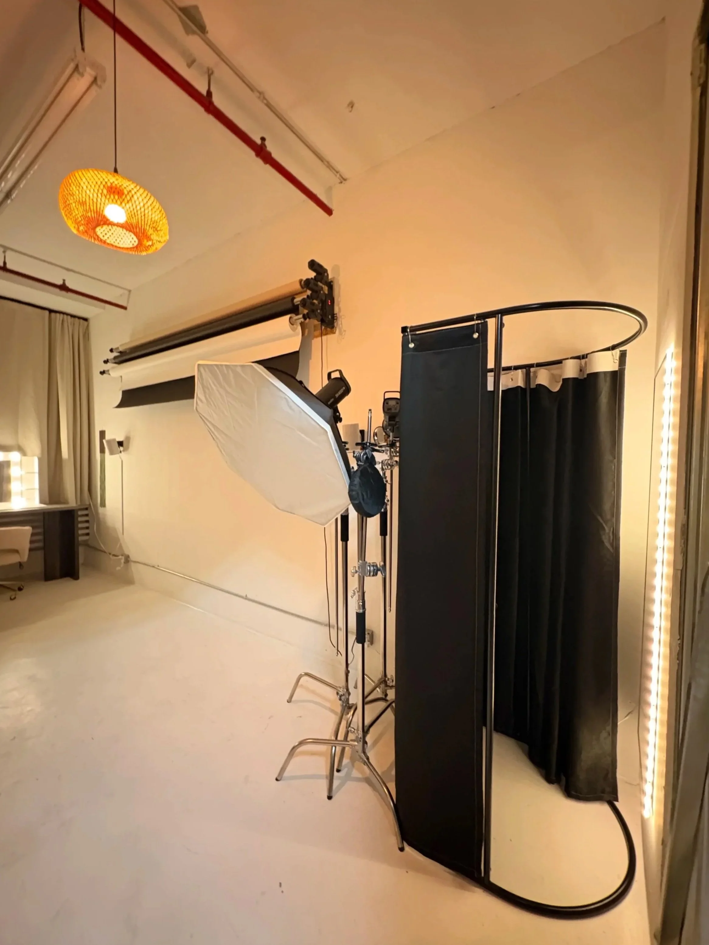 An indoor photography studio setup with lighting equipment, a backdrop, a black privacy screen, and other photographic tools.