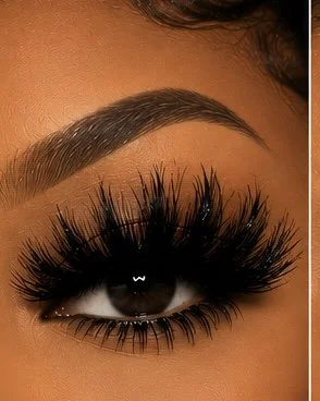 Close-up of a woman's eye with long, thick false eyelashes and well-groomed eyebrows.