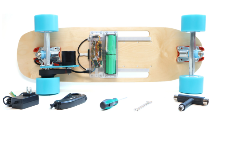 A wooden skateboard with mounted electronic components, two electric motors, and blue wheels, along with various tools and electronic parts placed below it.