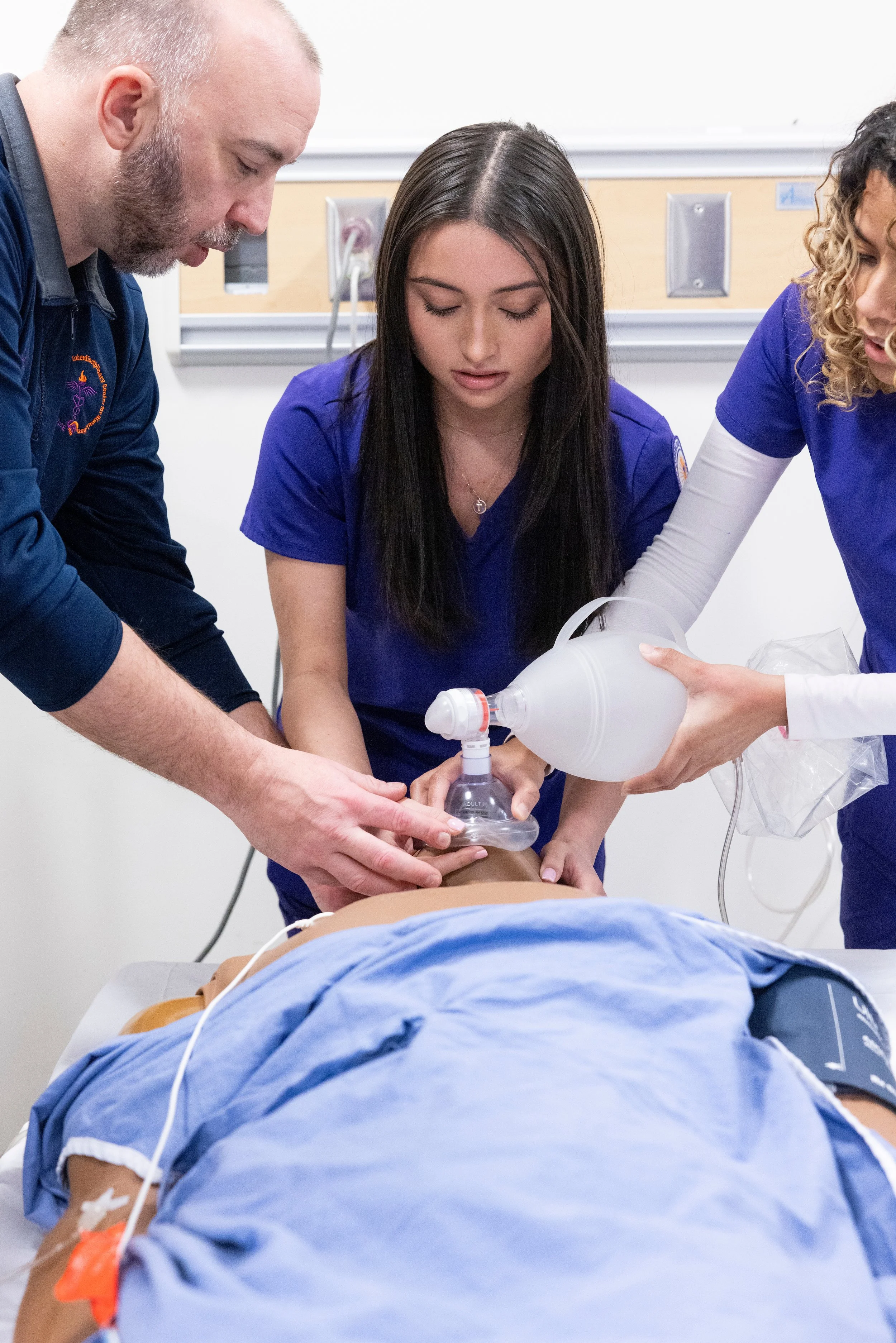 Medical professionals performing emergency medical procedures on a patient lying on a hospital bed, with a focus on their hands and medical equipment.