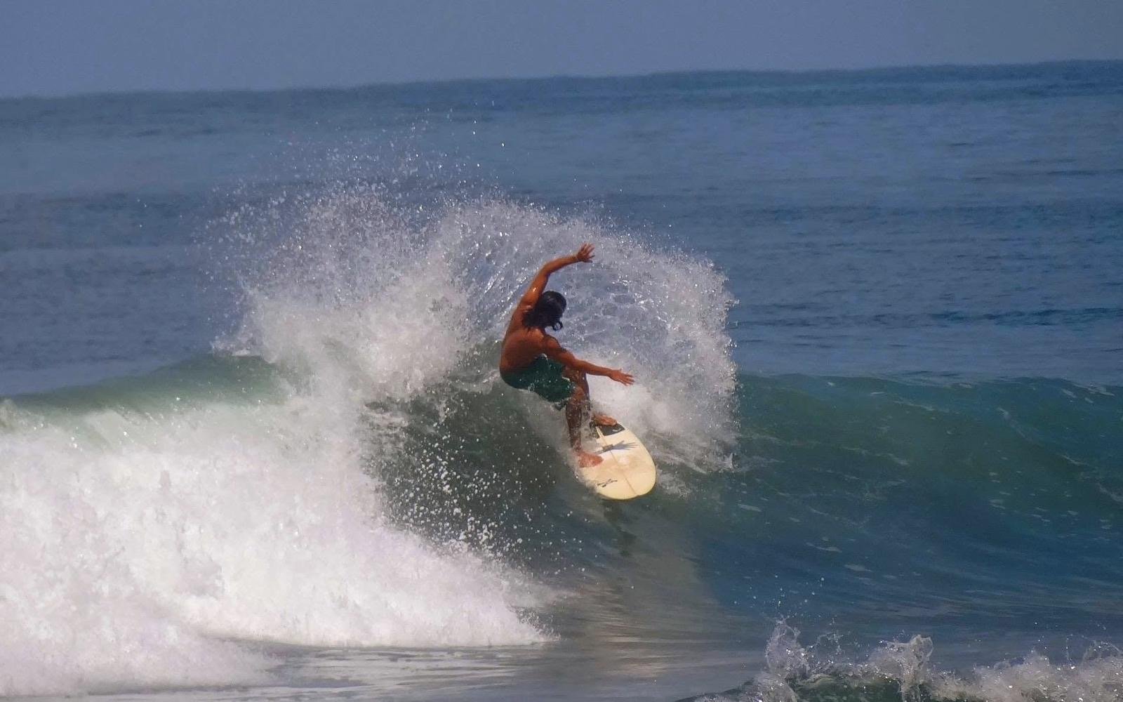 Person surfing on a wave in the ocean during daytime.