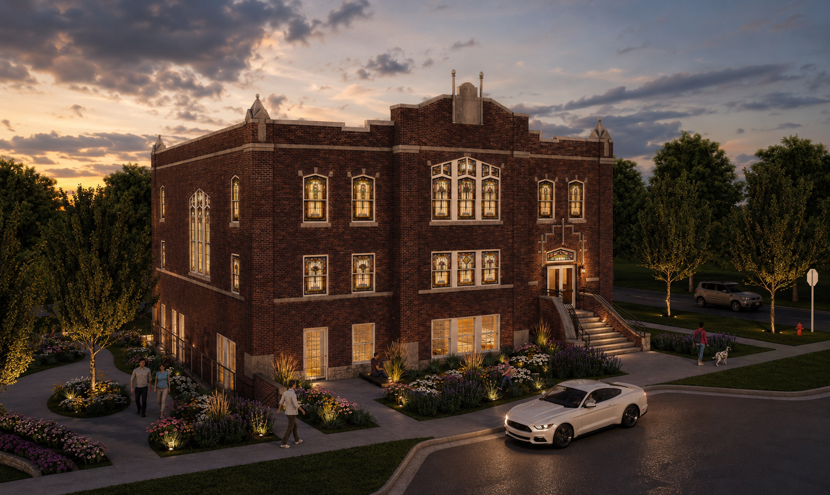 The Bradshaw historic event venue building at sunset with lit stained glass windows, floral gardens and pedestrians outside.