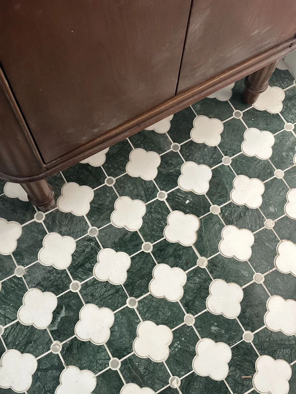 Green and white vintage inspired tile in a restroom with a dark wood vanity.