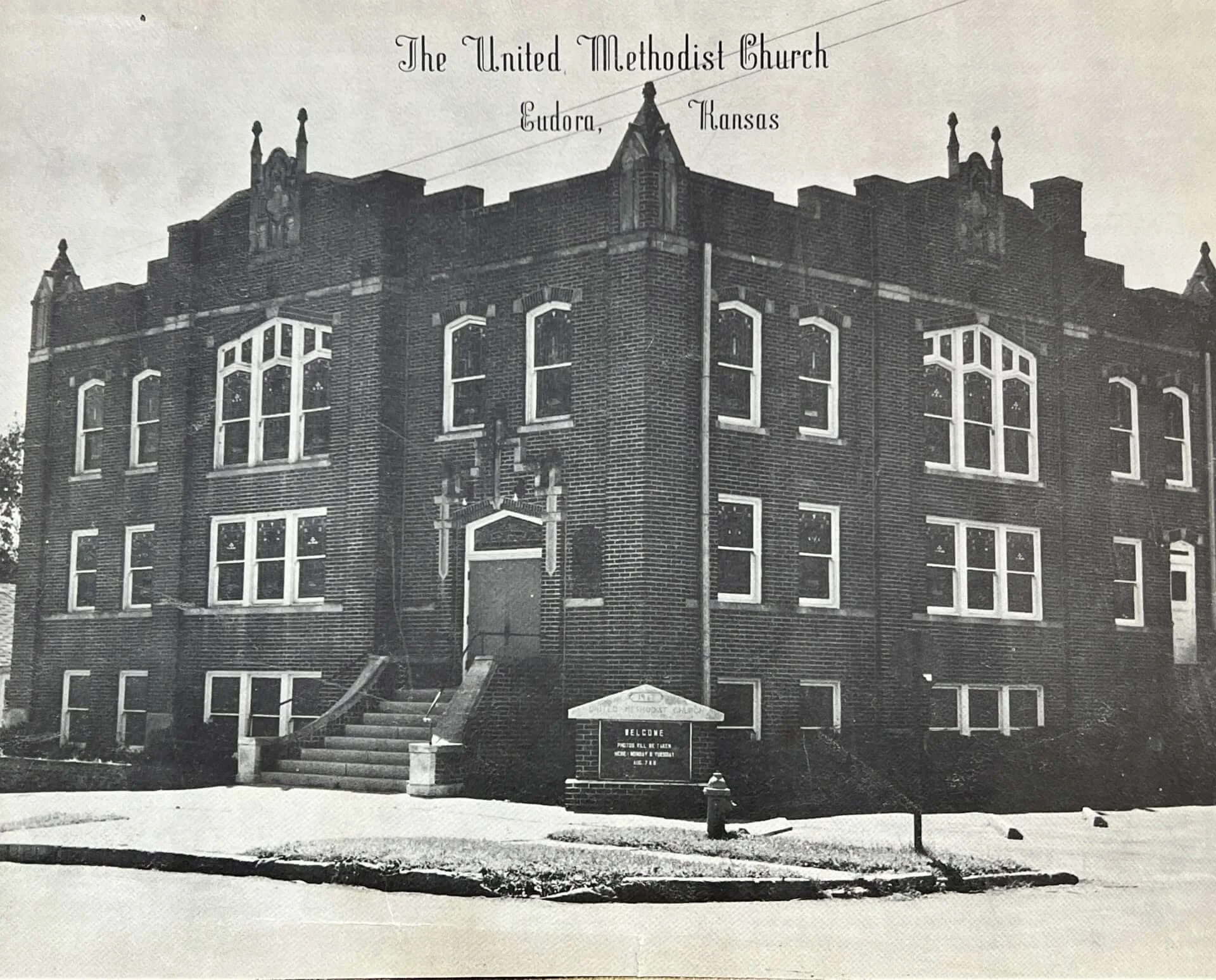 Black and white postcard of The United Methodist Church in Eudora, Kansas, a large brick church with pointed towers and arched windows.