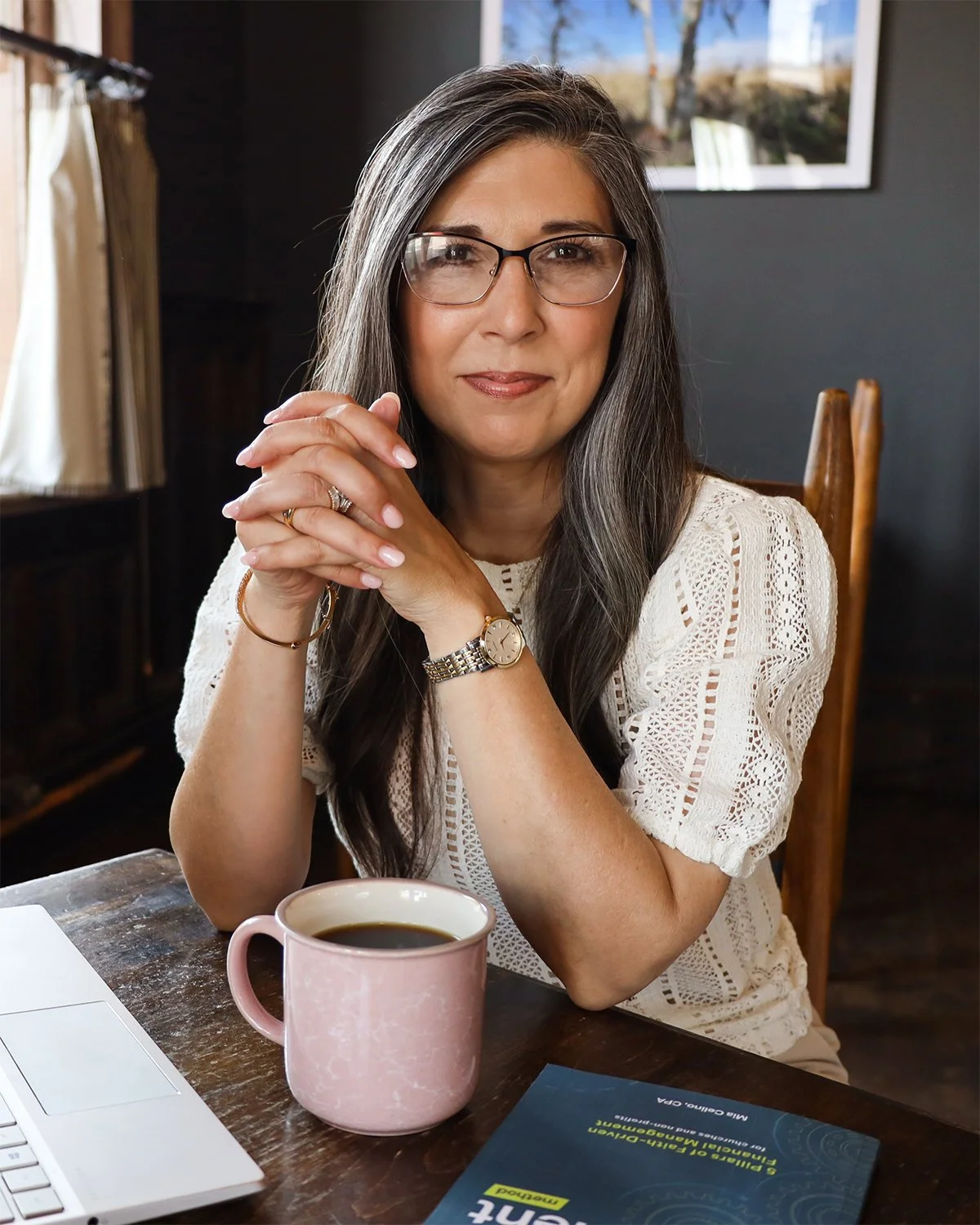 Mia Celino, CPA, founder of Align Consulting Group, sitting at a table with a laptop and her hands clasped in front of her