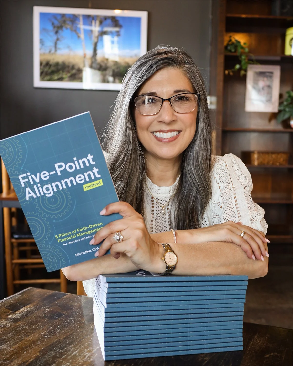 Mia Celino, CPA and founder of Align Consulting Group, holding a stack of her Five-Point Alignment Method books