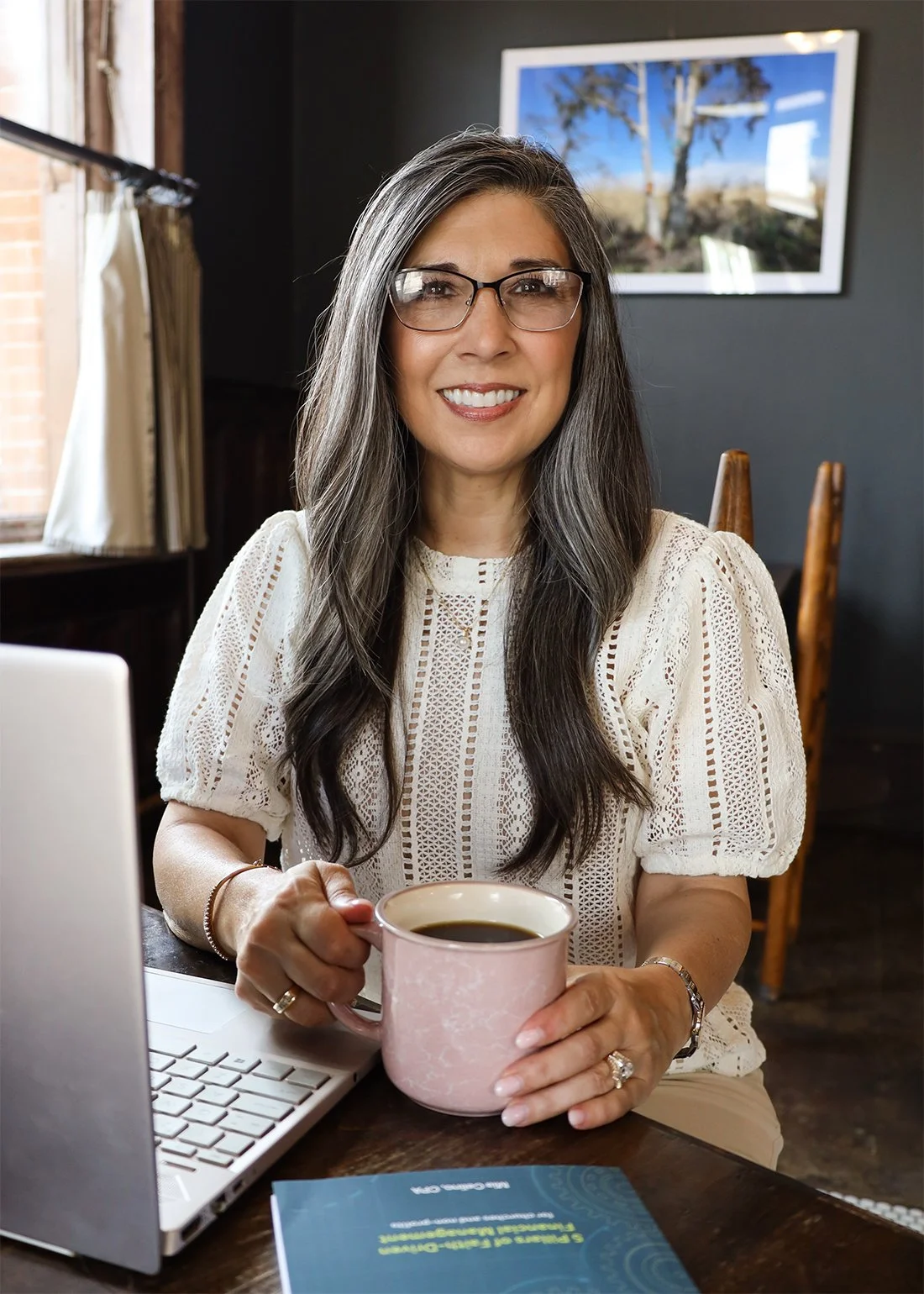 Mia Celino, CPA, founder of Align Consulting Group, sitting at a table with a laptop and a cup of coffee in hand