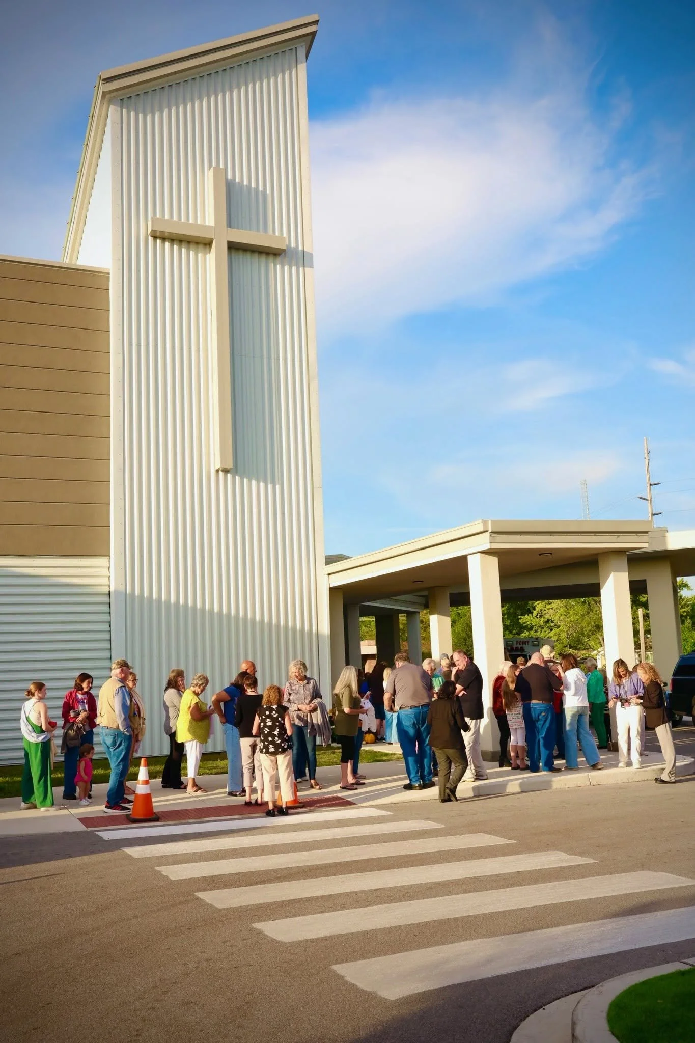 The congregation at Living Stones Church in Crown Point, IN, walking into the church with a large cross on the building