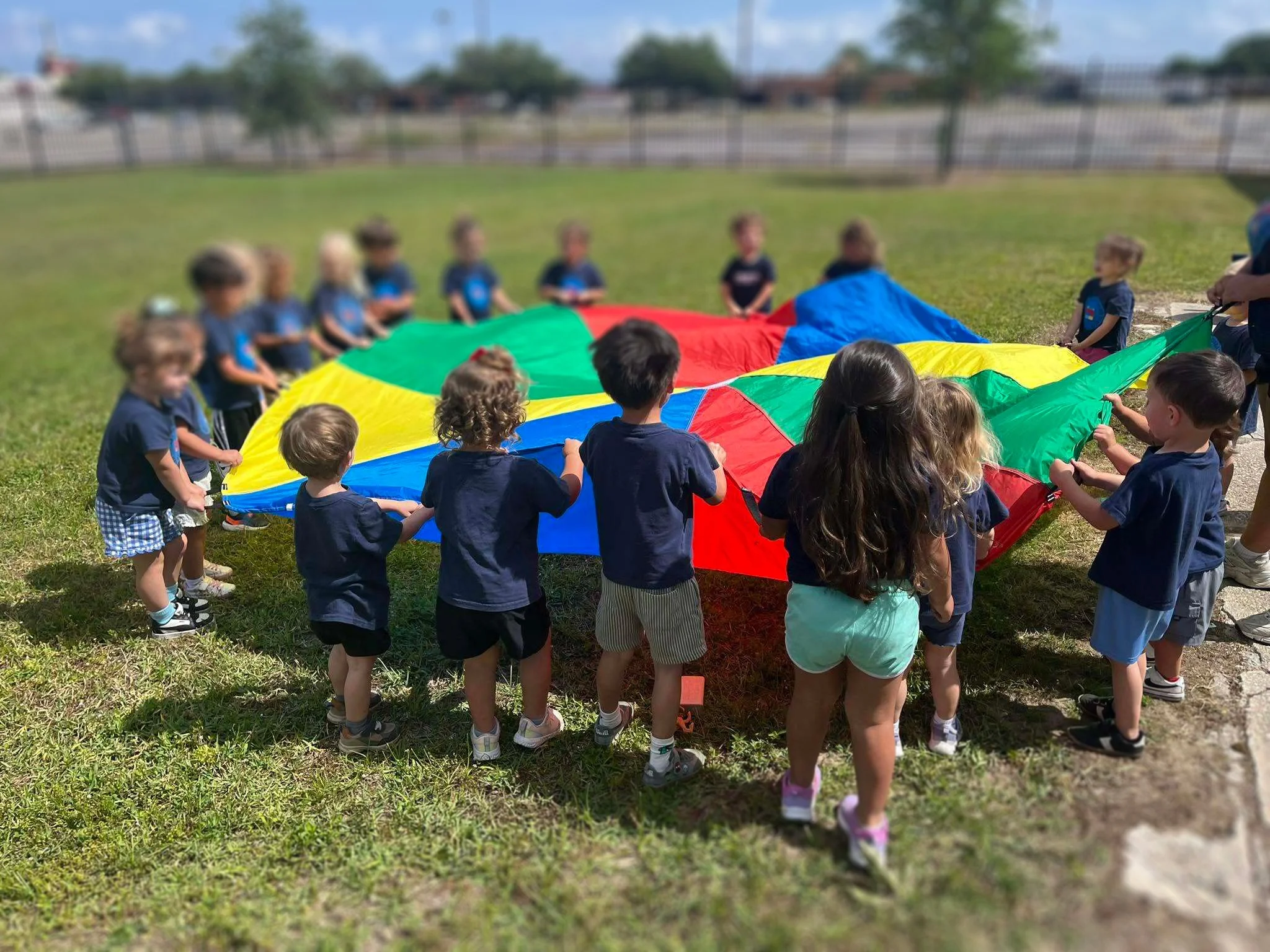Young children playing with a colorful parachute at the Primary Early Education Center