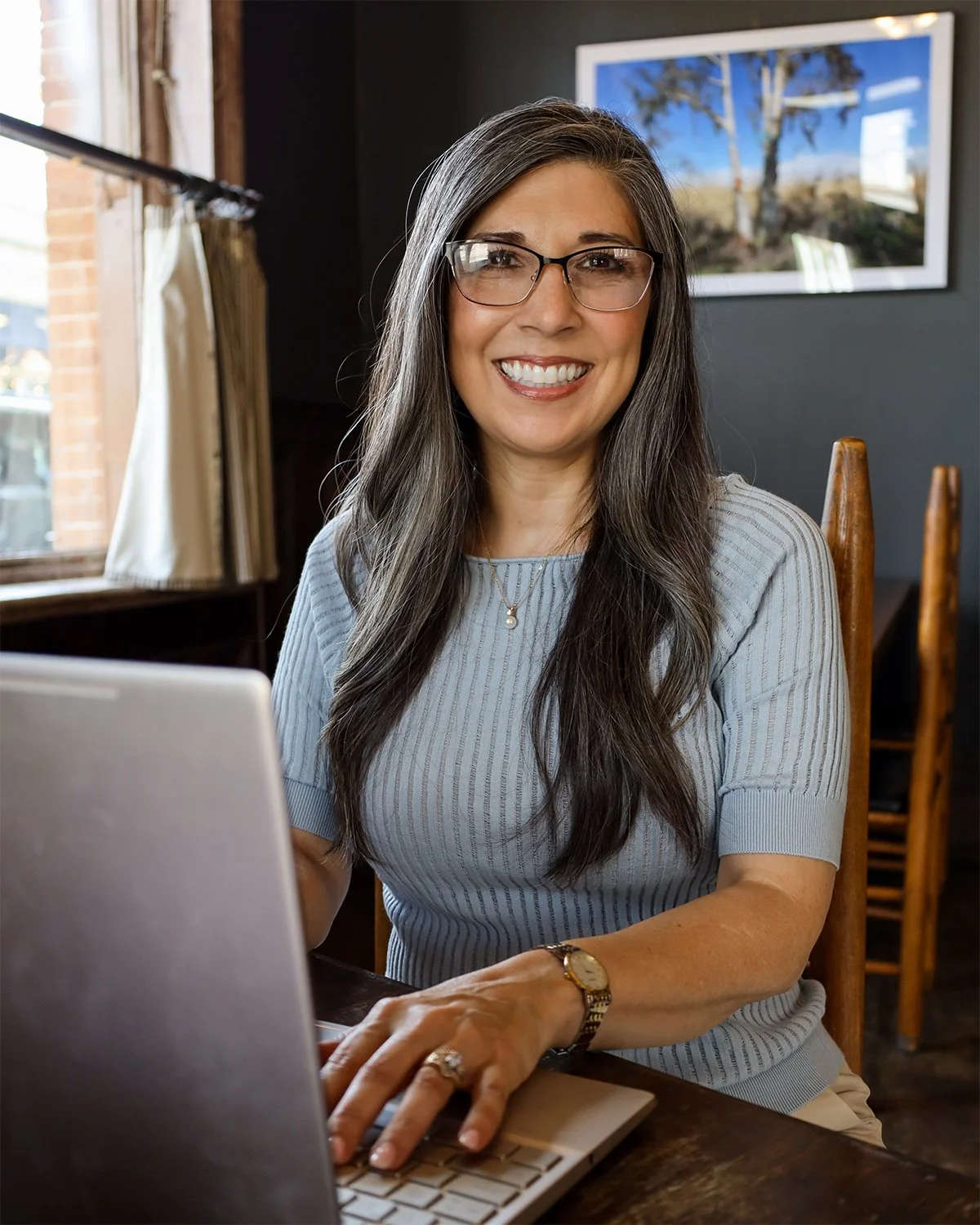 Mia Celino, CPA, reviewing financial reports on a laptop while smiling at the camera