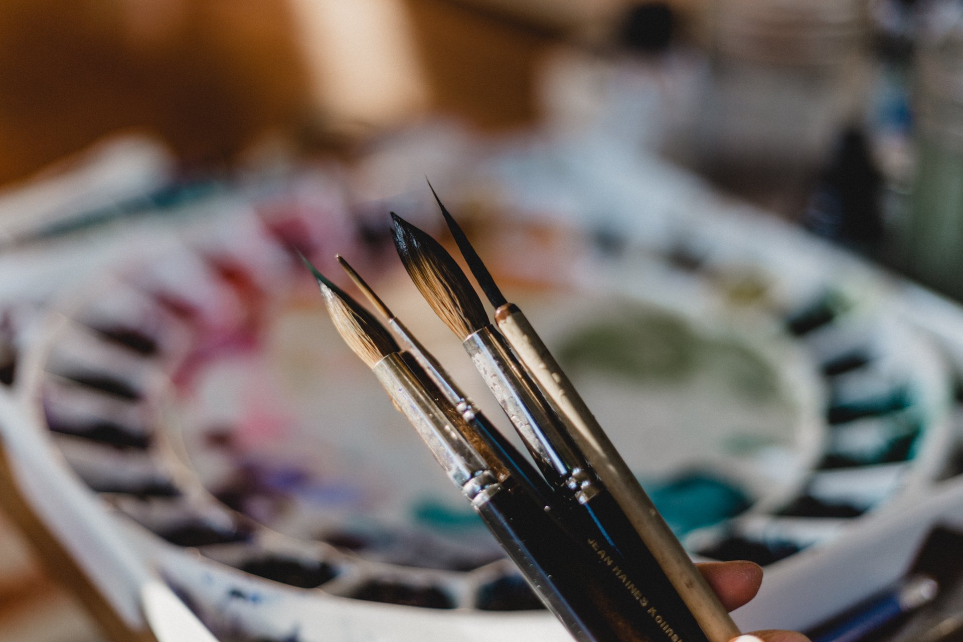 Close-up of paintbrushes resting in a paint palette with various colors.