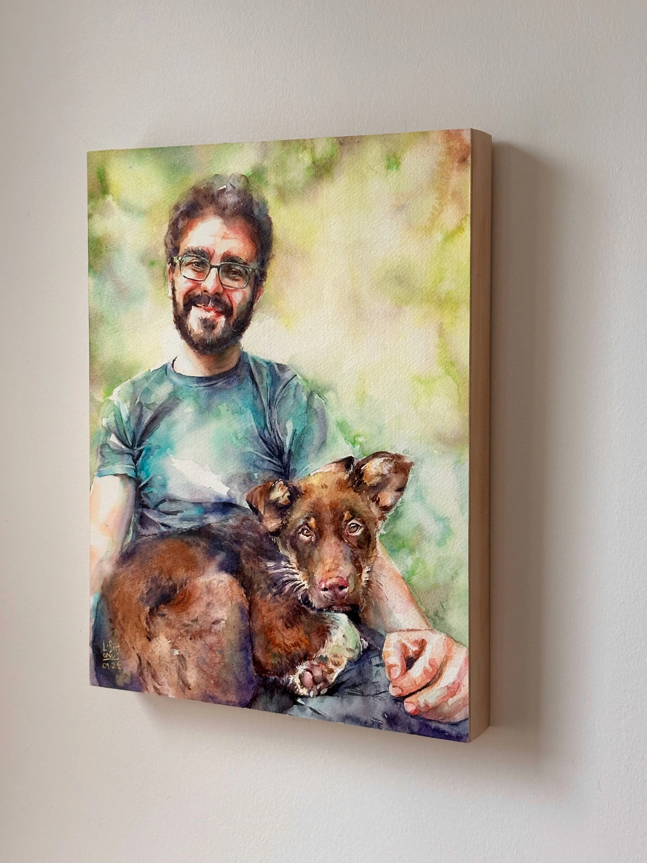 Watercolor painting of a man with glasses and dark hair, holding a brown dog with floppy ears, against a green and yellow blurred background.
