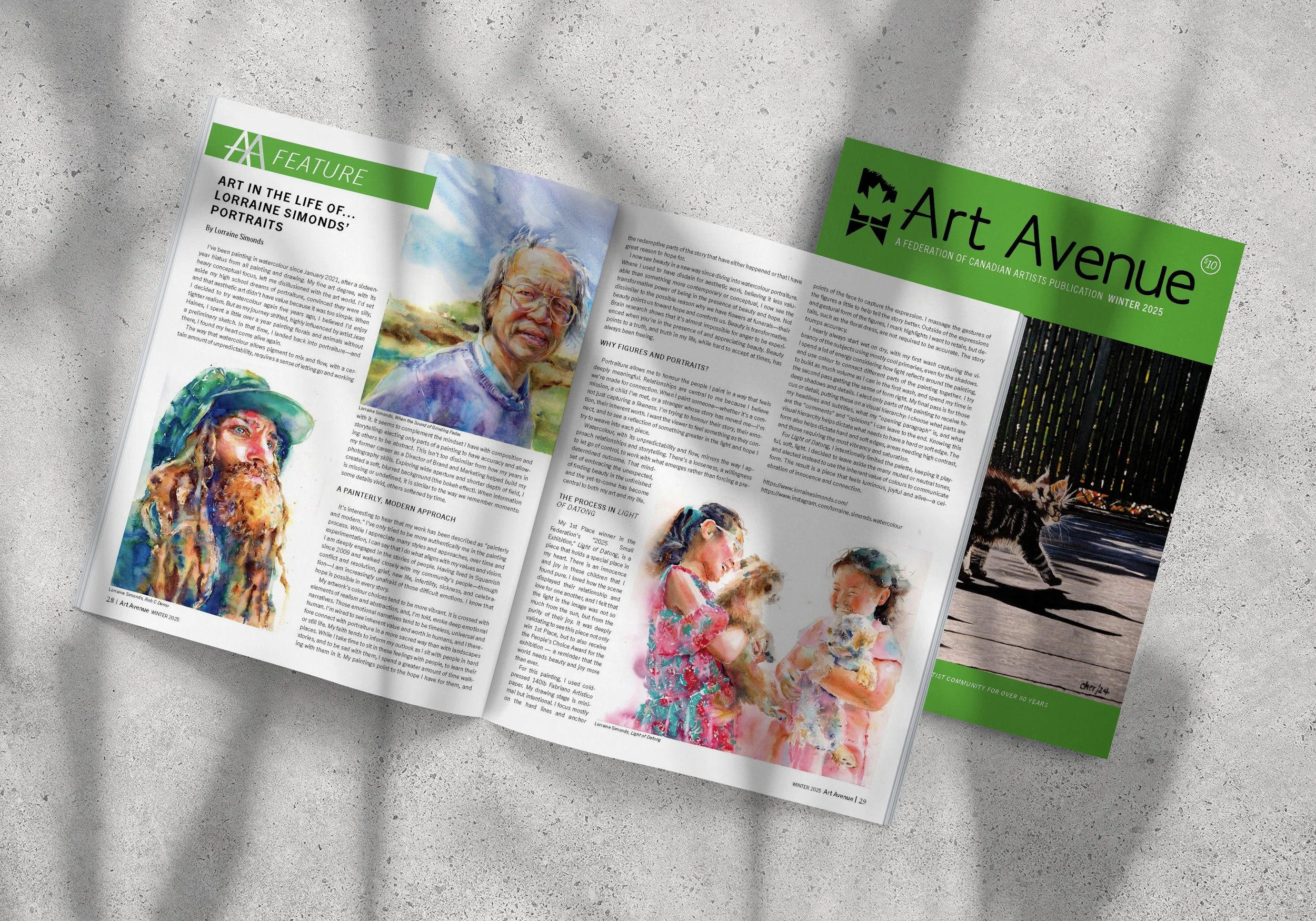 Open art magazine showing watercolor portraits of elderly people, laid on a gray surface with shadows.