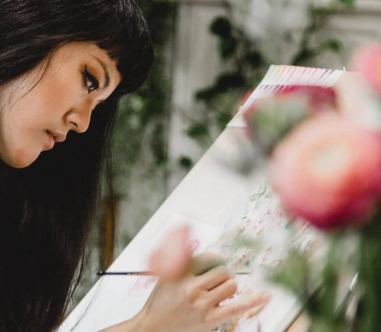 Lorraine Simonds is painting loose watercolour florals with blurred pink flowers in the foreground.