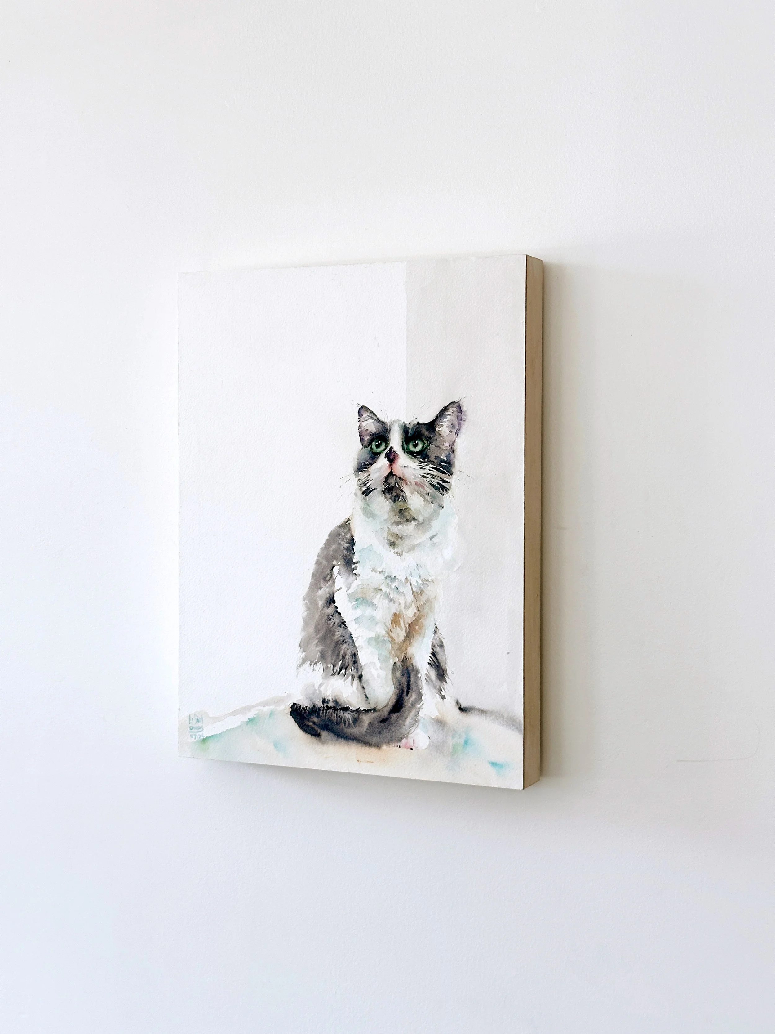 Watercolor painting of a cat with green eyes, sitting and looking upward, on a white background.