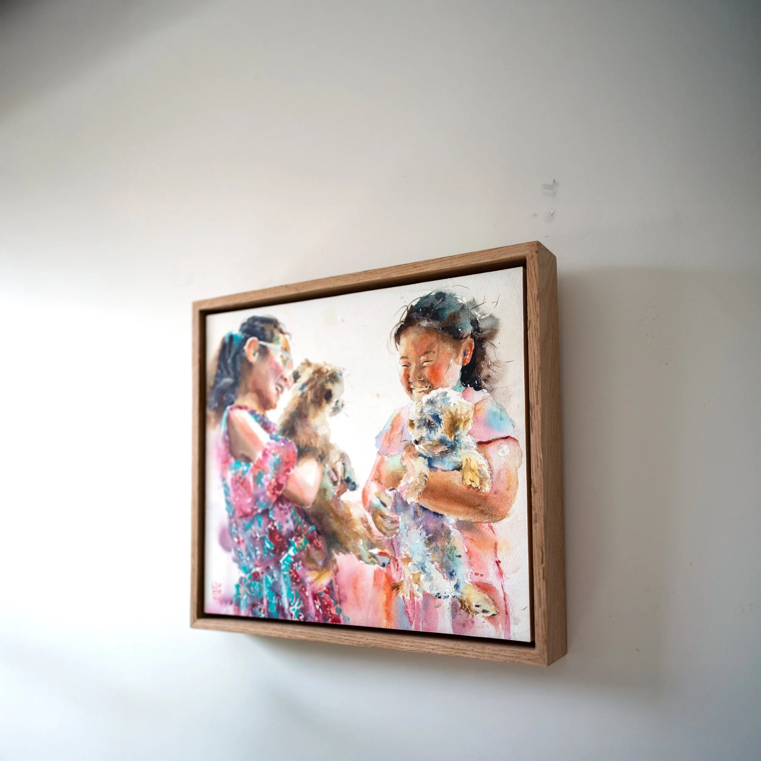 Watercolor painting of people with vibrant colors and loose brushstrokes, framed in wood and hanging on a plain white wall.