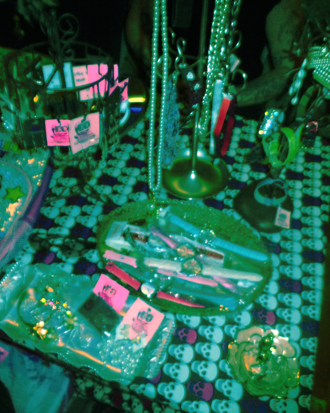 Display of jewelry and accessories on a skull-themed tablecloth with neon lighting.