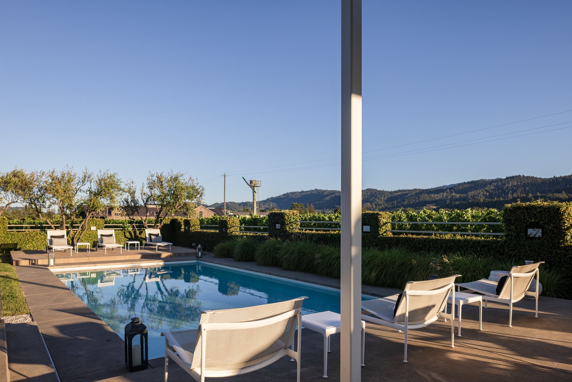 Outdoor pool area with lounge chairs, umbrellas, and a scenic mountain view