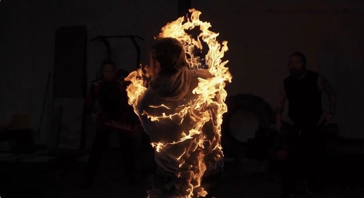 A person performing a fire spinning act in a dark room, surrounded by fire.