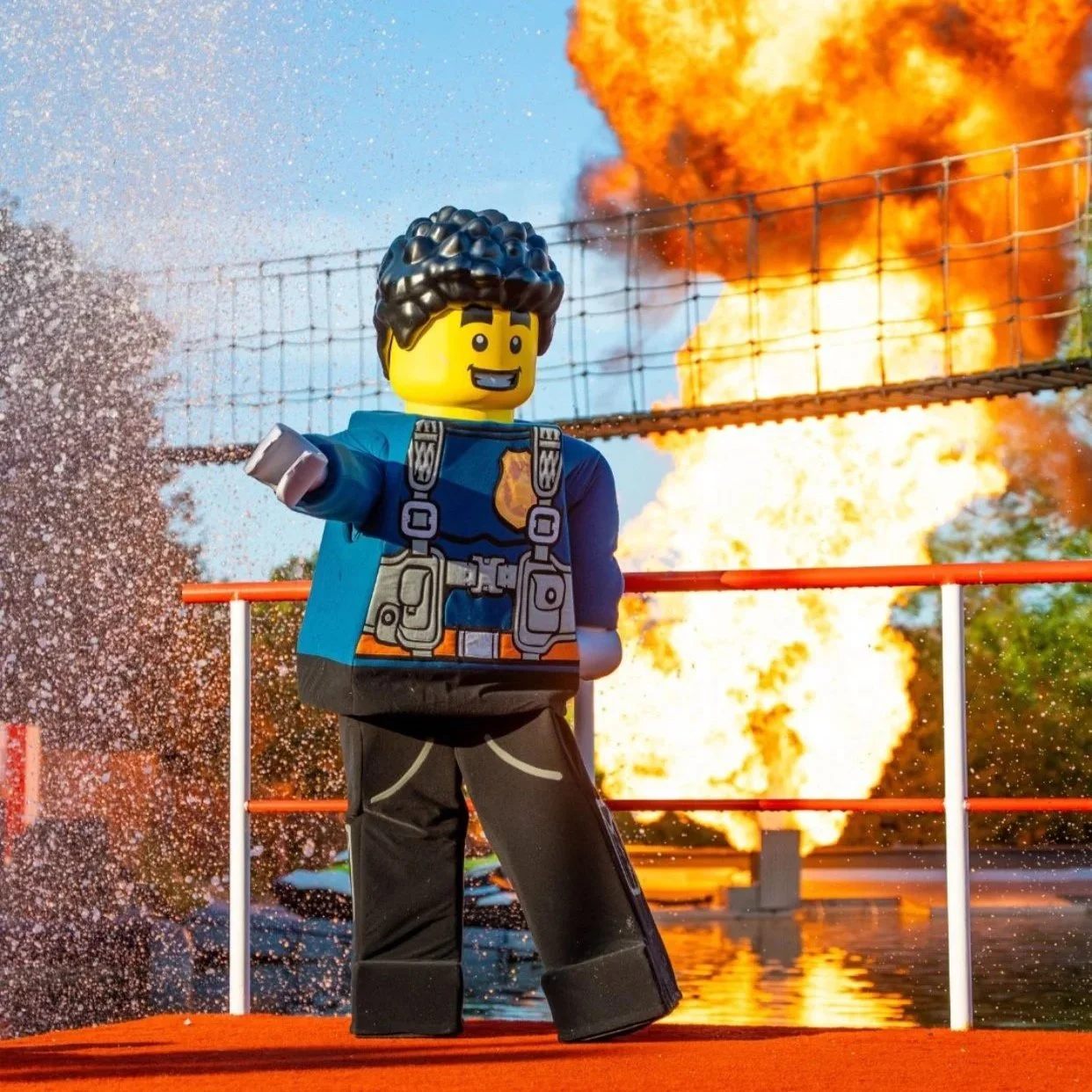 Lego police officer figurine in front of an explosion with flames and fire in the background.